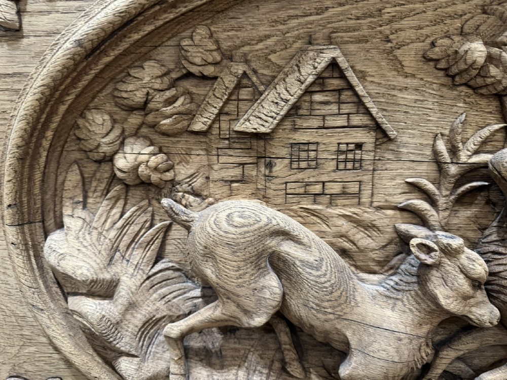 A light oak sideboard with detailed relief carvings of deer in a forest setting on the central panel, flanked by foliage motifs. View XV
