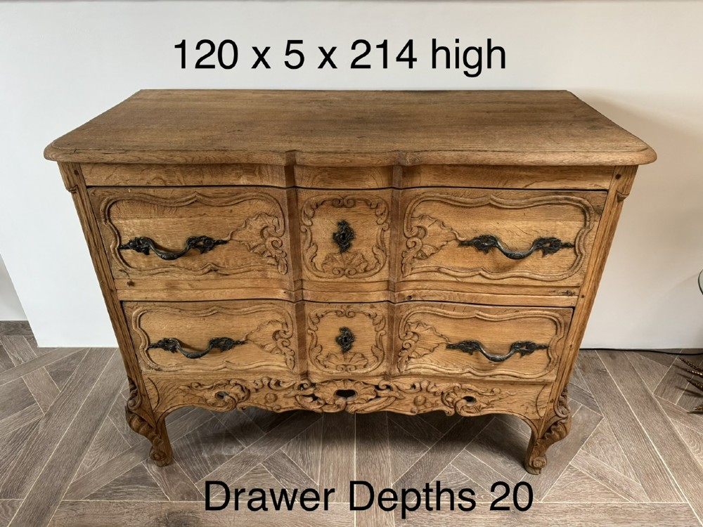 A French bleached oak two-drawer commode featuring carved foliate panels, cabriole legs, and dark metal handles. View III