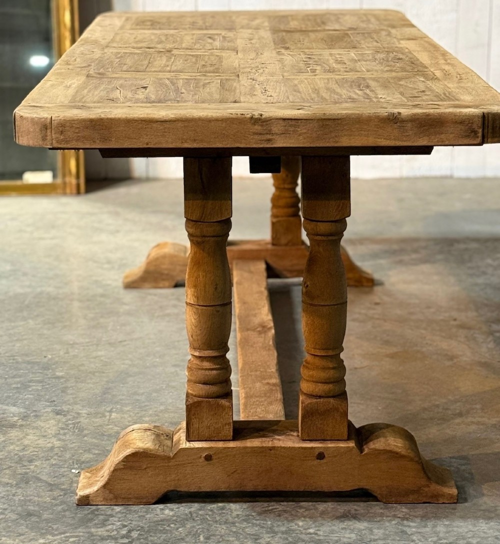 A rectangular French oak dining table featuring a parquetry top, twin turned pedestal legs, and a low central stretcher base. View XI