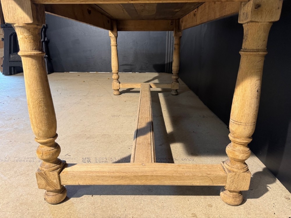 A light natural oak farmhouse dining table featuring turned legs, an H-stretcher base, and a planked top with cleated breadboard ends. View IV