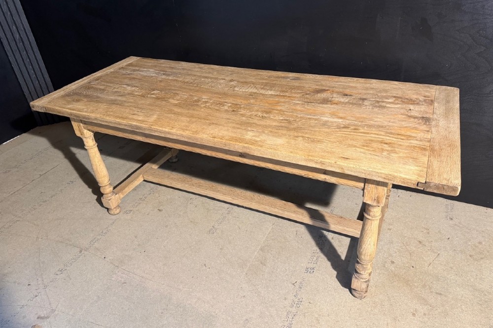 A light natural oak farmhouse dining table featuring turned legs, an H-stretcher base, and a planked top with cleated breadboard ends. View VII