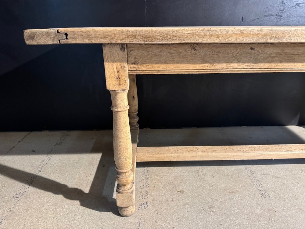 A light natural oak farmhouse dining table featuring turned legs, an H-stretcher base, and a planked top with cleated breadboard ends. View X