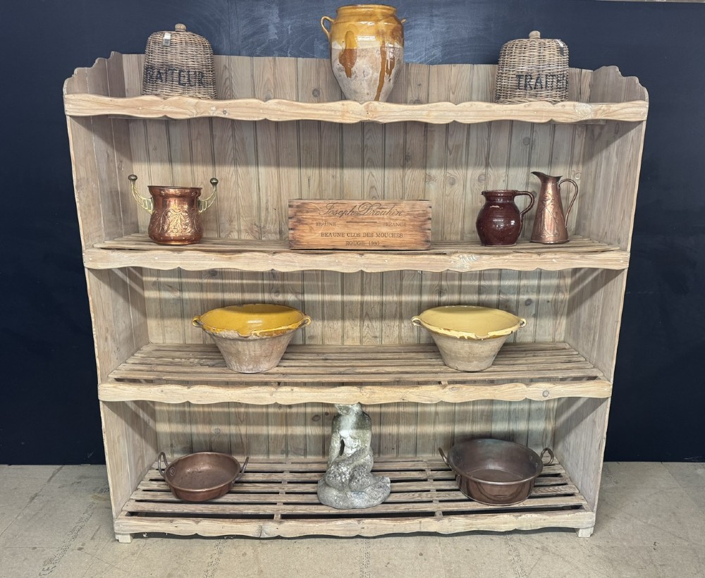 A large 19th-century French pine bakers rack featuring four slatted timber shelves and scalloped front aprons.