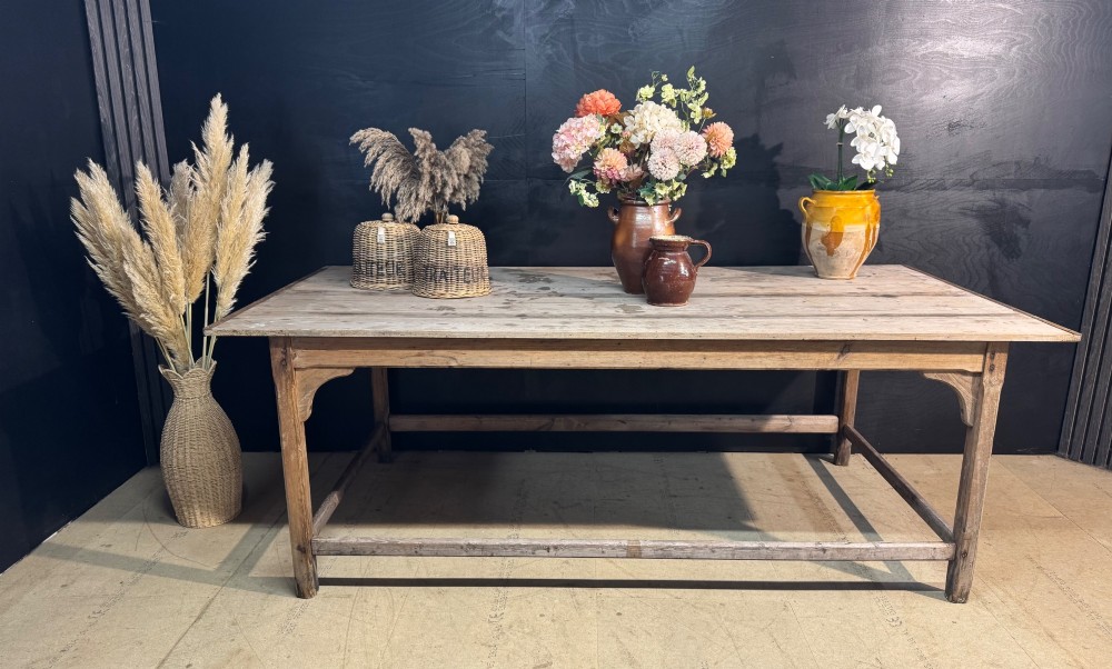 A large rustic wooden French prep table featuring a weathered scrubbed timber top, corner support brackets, and low perimeter stretchers.