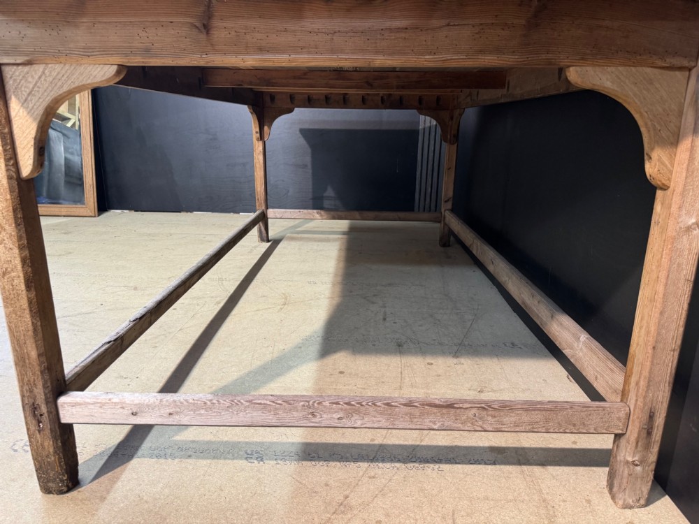 A large rustic wooden French prep table featuring a weathered scrubbed timber top, corner support brackets, and low perimeter stretchers. View X