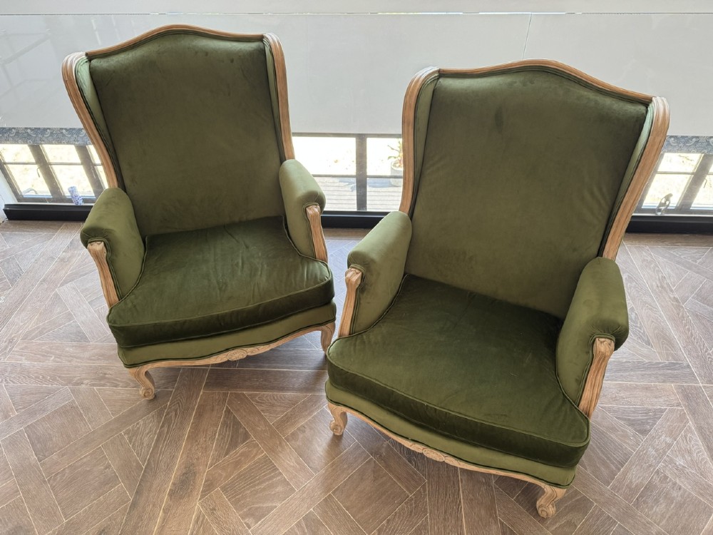 A pair of French wingback armchairs upholstered in olive green velvet with carved timber frames and cabriole legs. View II