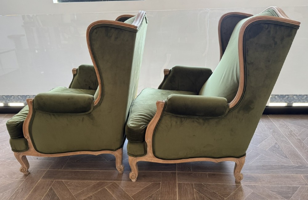 A pair of French wingback armchairs upholstered in olive green velvet with carved timber frames and cabriole legs. View VI