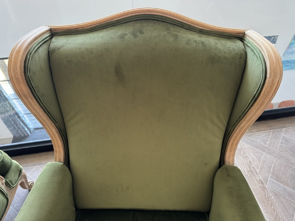 A pair of French wingback armchairs upholstered in olive green velvet with carved timber frames and cabriole legs. View X