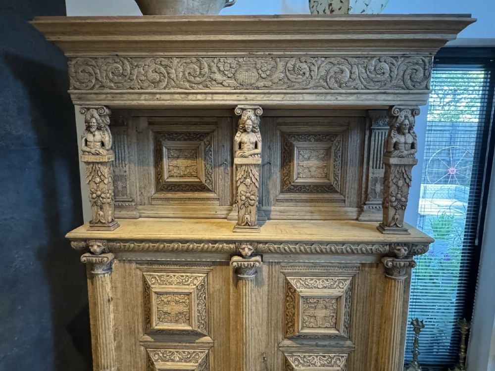 An 18th-century Flemish carved oak cabinet featuring detailed figurative columns, geometric door panels, lion head motifs, and bun feet. View IV