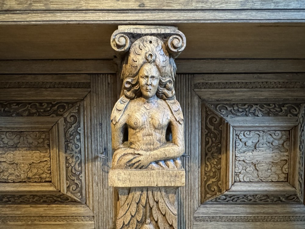 An 18th-century Flemish carved oak cabinet featuring detailed figurative columns, geometric door panels, lion head motifs, and bun feet. View V