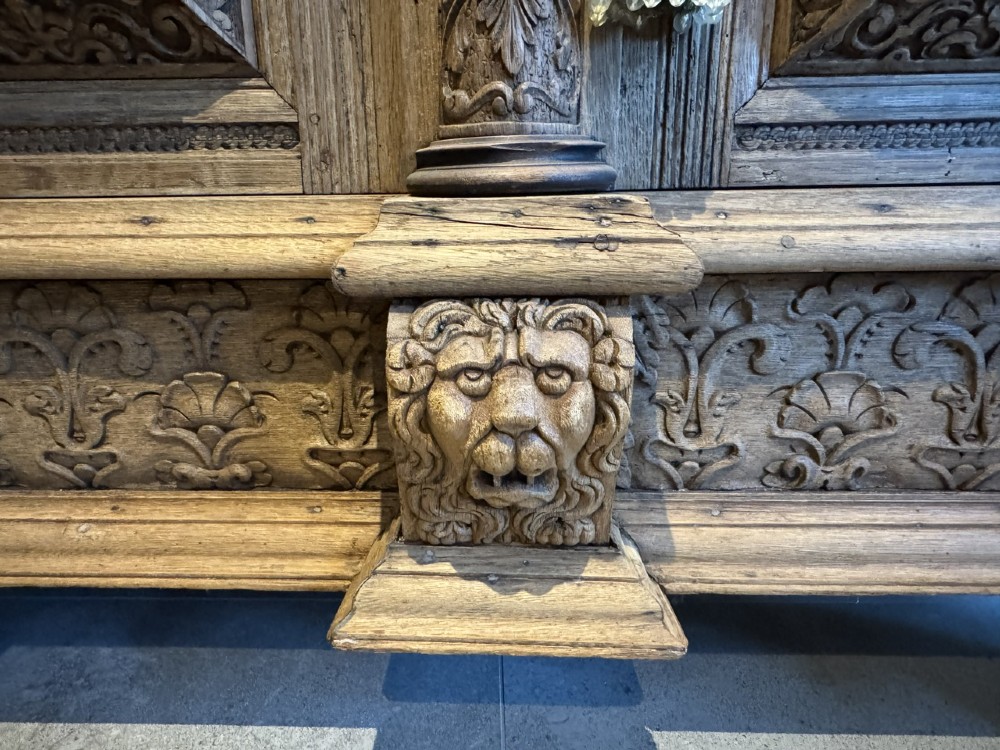 An 18th-century Flemish carved oak cabinet featuring detailed figurative columns, geometric door panels, lion head motifs, and bun feet. View VII