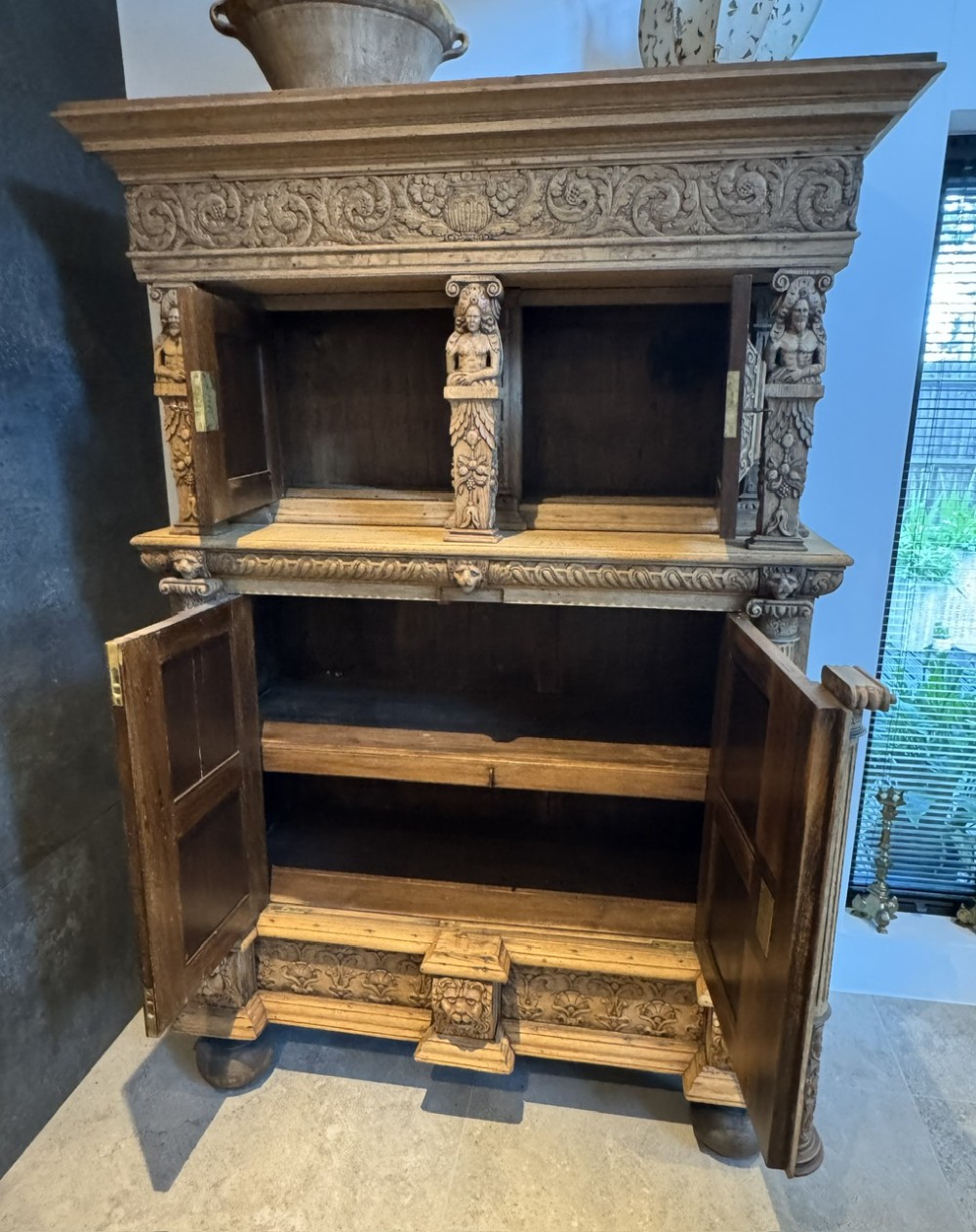 An 18th-century Flemish carved oak cabinet featuring detailed figurative columns, geometric door panels, lion head motifs, and bun feet. View VIII