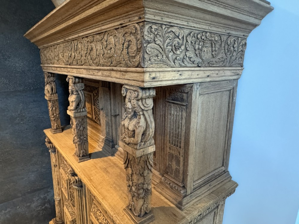 An 18th-century Flemish carved oak cabinet featuring detailed figurative columns, geometric door panels, lion head motifs, and bun feet. View XIII