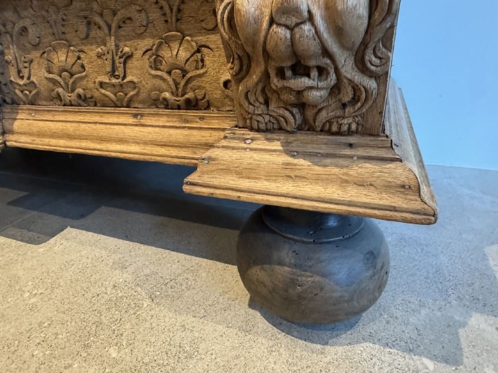An 18th-century Flemish carved oak cabinet featuring detailed figurative columns, geometric door panels, lion head motifs, and bun feet. View XIV