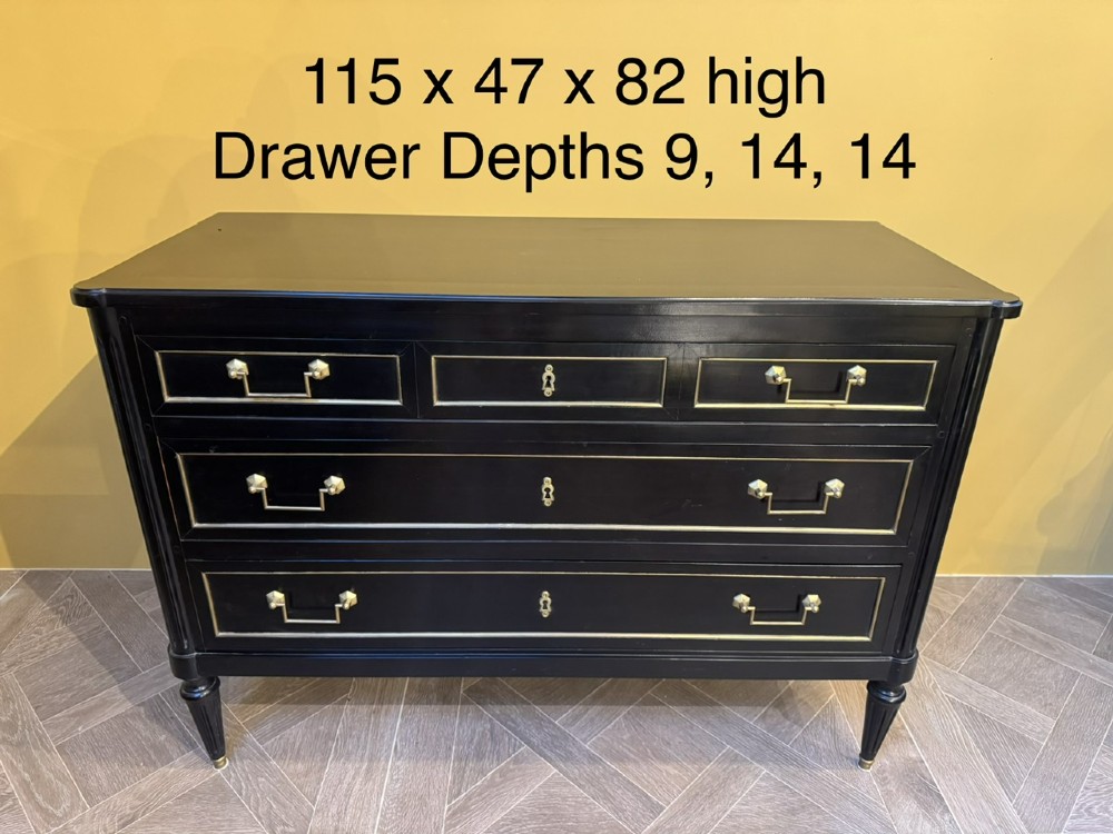A French Louis XVI style ebonised commode featuring three tiers of drawers detailed with geometric brass trim and supported by tapered fluted legs. View XII