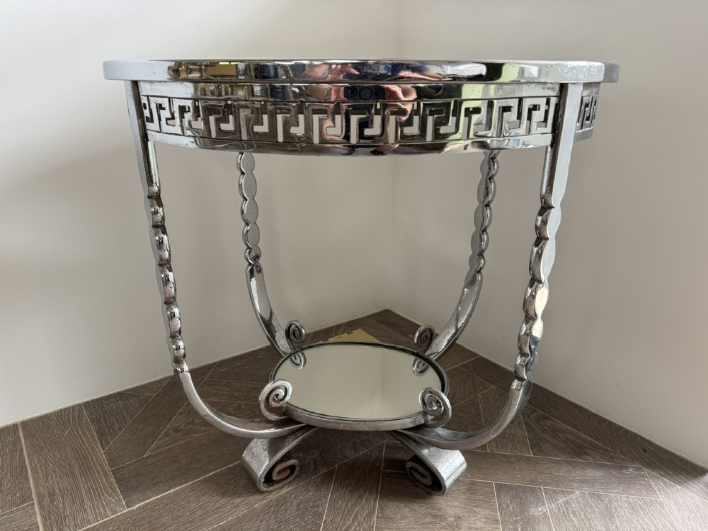 A circular chrome Art Deco side table featuring a mirrored glass top, Greek key frieze pattern, lower tier mirror, and scroll-footed legs. View II