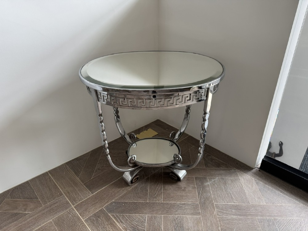 A circular chrome Art Deco side table featuring a mirrored glass top, Greek key frieze pattern, lower tier mirror, and scroll-footed legs. View VIII