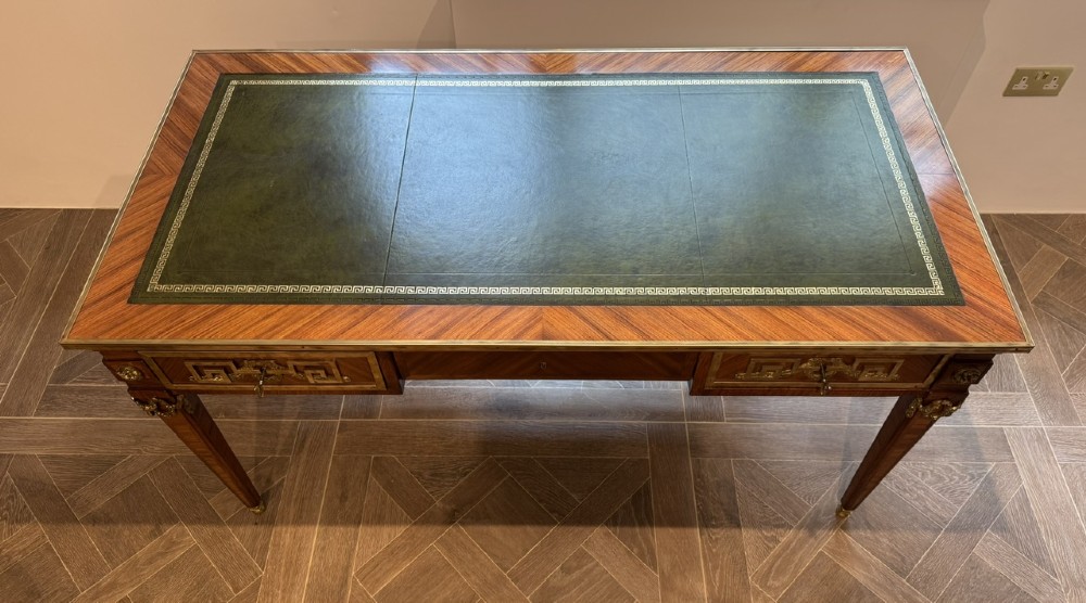 A French Louis XVI style writing desk featuring a green leather insert, wood parquetry veneer, three frieze drawers, and gilt bronze mounts. View III