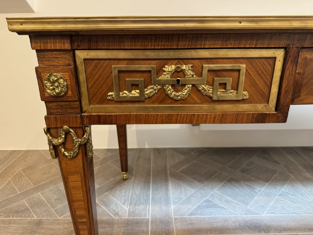 A French Louis XVI style writing desk featuring a green leather insert, wood parquetry veneer, three frieze drawers, and gilt bronze mounts. View V