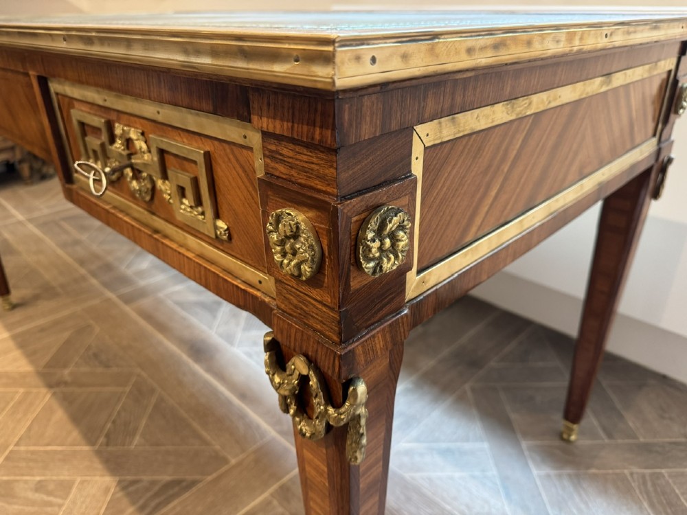 A French Louis XVI style writing desk featuring a green leather insert, wood parquetry veneer, three frieze drawers, and gilt bronze mounts. View VI
