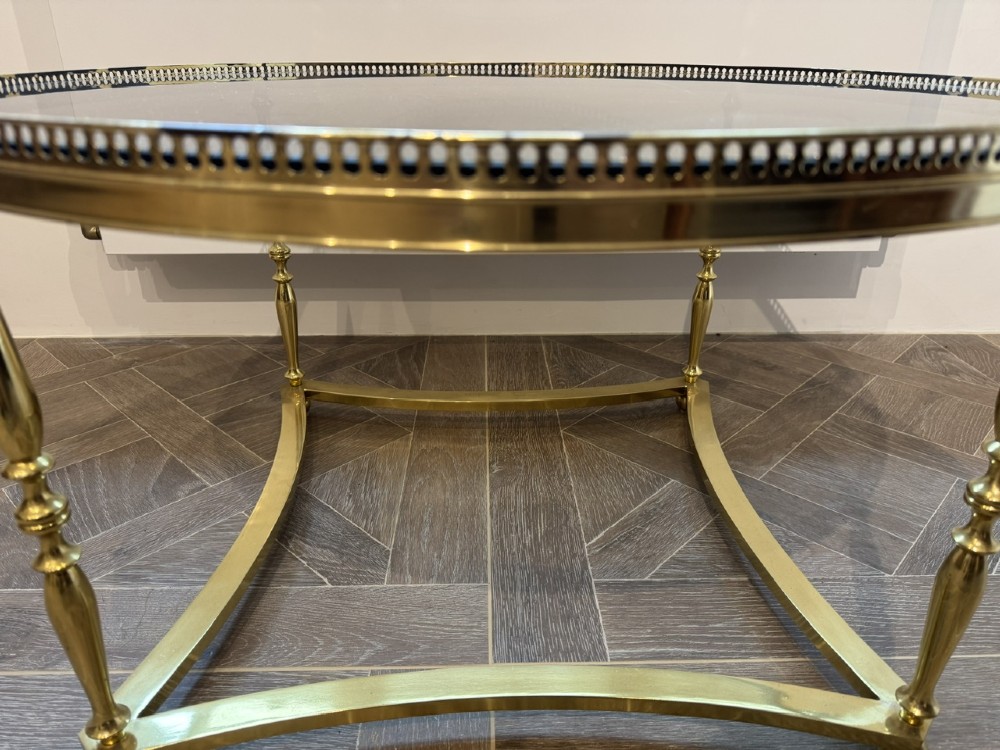 A circular brass coffee table featuring a dark smoked glass top, a pierced gallery rim, turned legs, and a curved stretcher base. View V