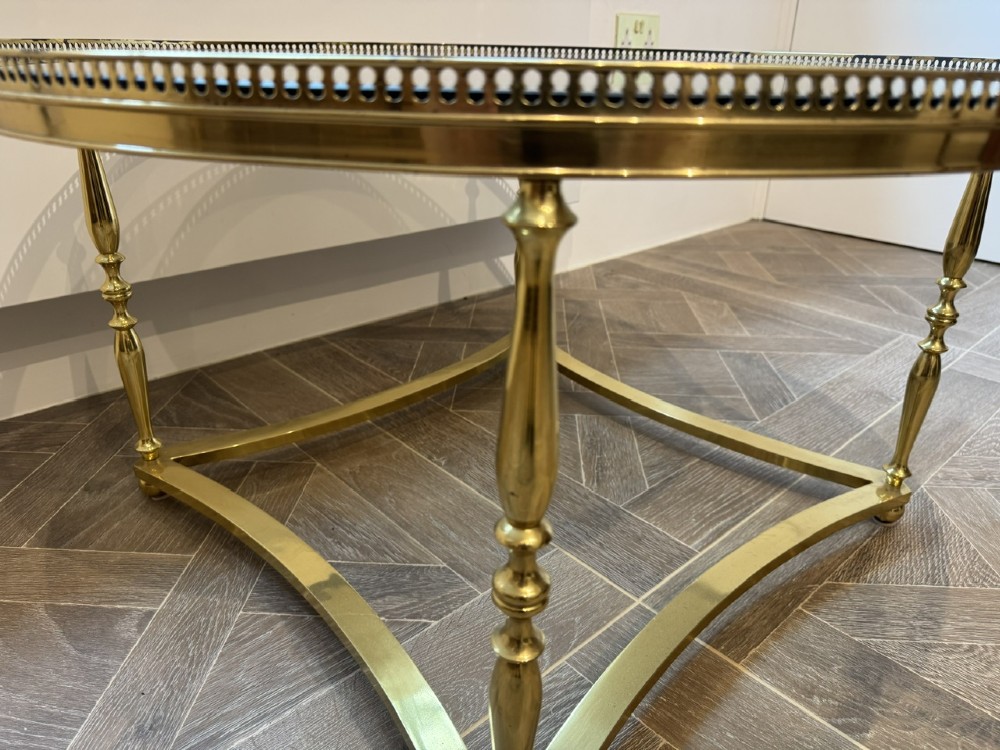 A circular brass coffee table featuring a dark smoked glass top, a pierced gallery rim, turned legs, and a curved stretcher base. View VII