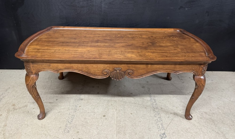 A burr walnut low coffee table featuring cabriole legs, a carved shell motif on the central apron, and a raised moulded edge around the top.