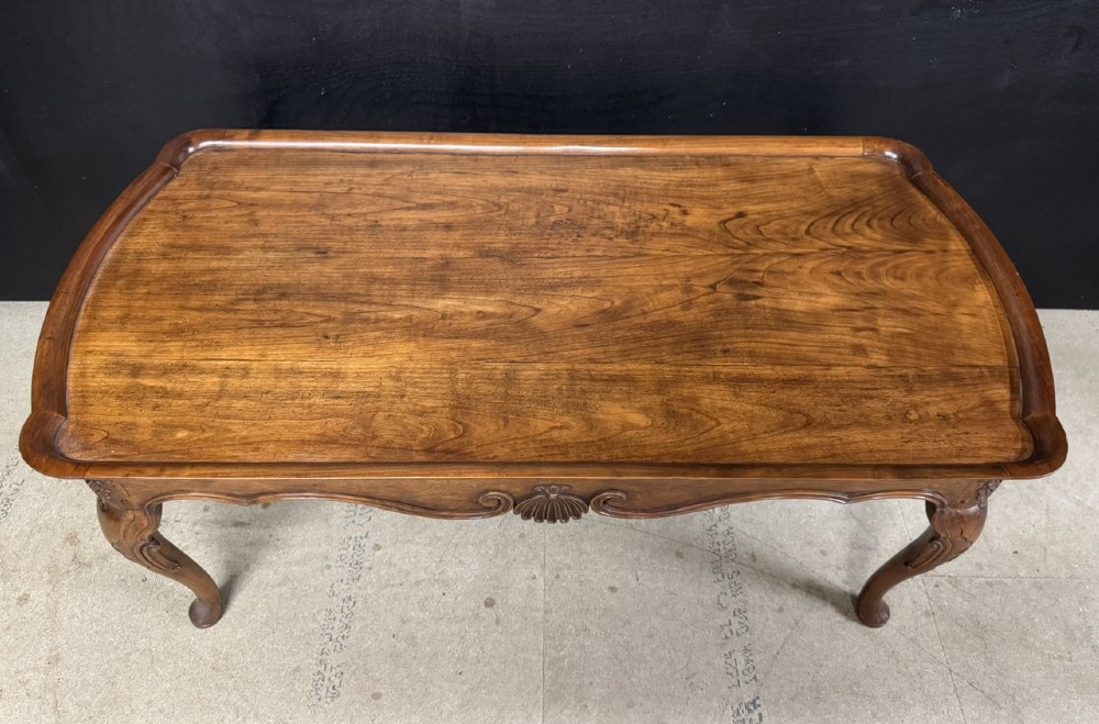 A burr walnut low coffee table featuring cabriole legs, a carved shell motif on the central apron, and a raised moulded edge around the top. View II