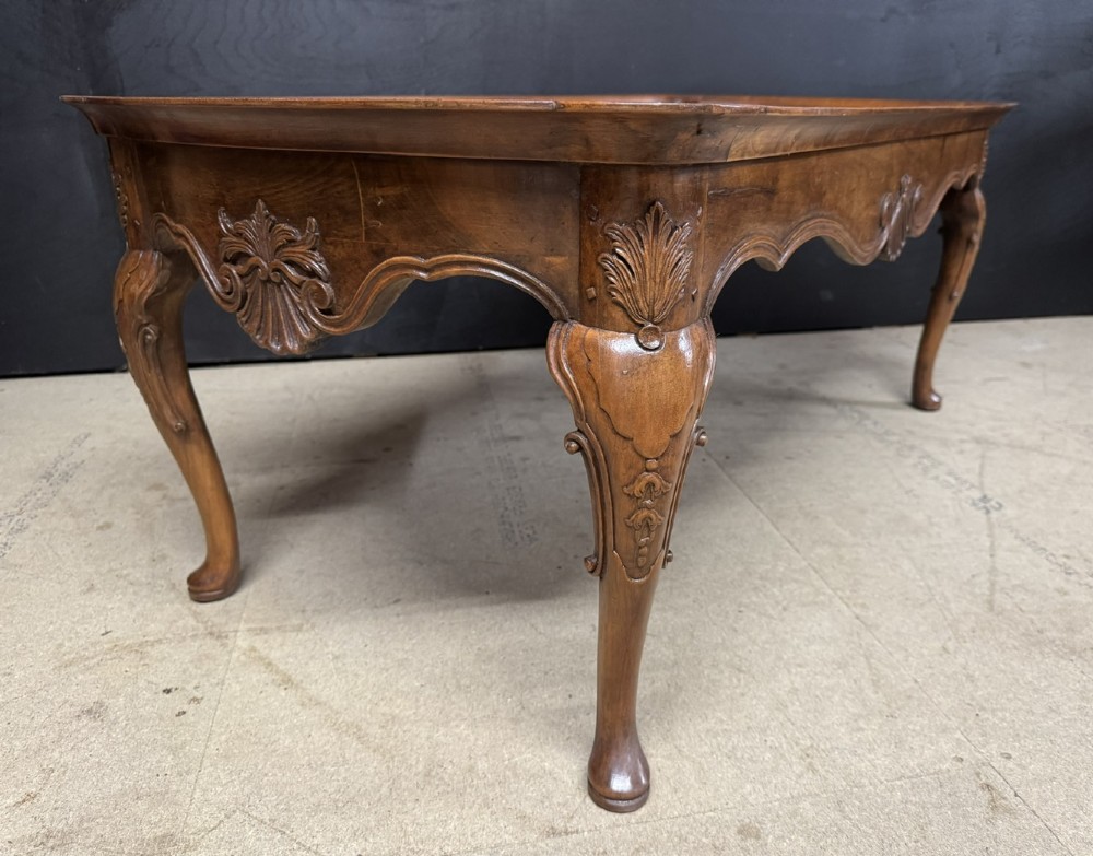 A burr walnut low coffee table featuring cabriole legs, a carved shell motif on the central apron, and a raised moulded edge around the top. View IV