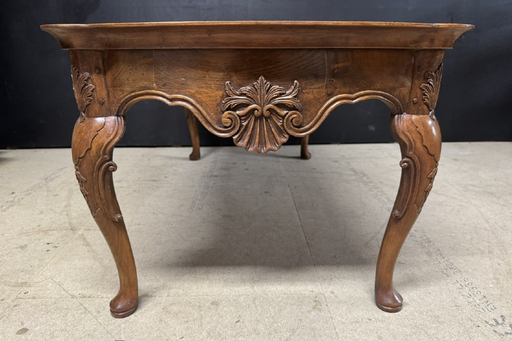 A burr walnut low coffee table featuring cabriole legs, a carved shell motif on the central apron, and a raised moulded edge around the top. View VII