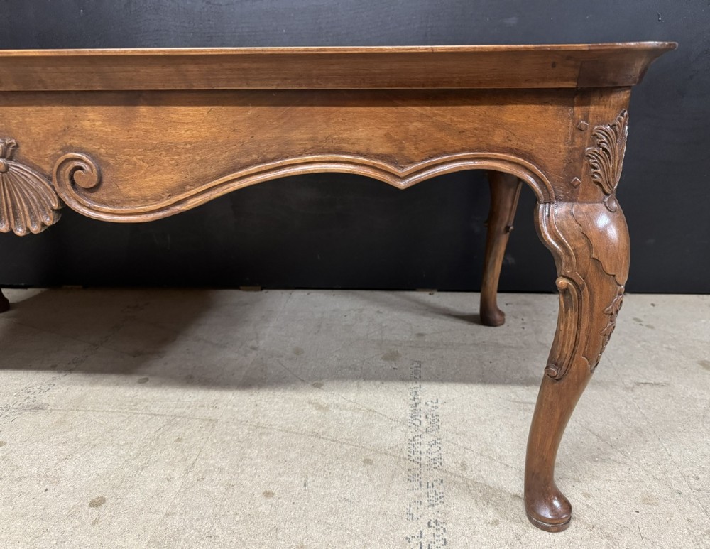 A burr walnut low coffee table featuring cabriole legs, a carved shell motif on the central apron, and a raised moulded edge around the top. View XI