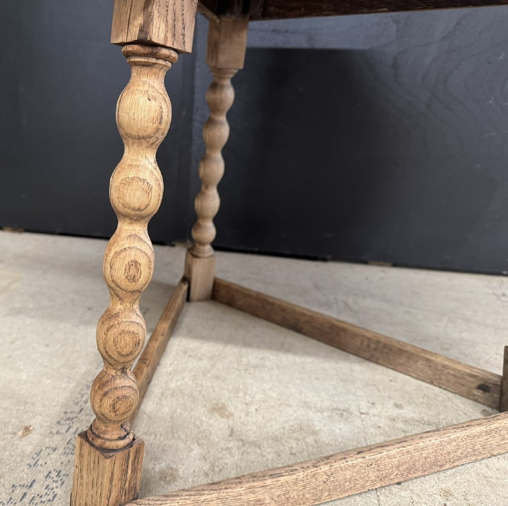 A hexagonal carved oak cricket table featuring elaborate foliate scrollwork on the tabletop and three turned legs joined by stretchers. View III
