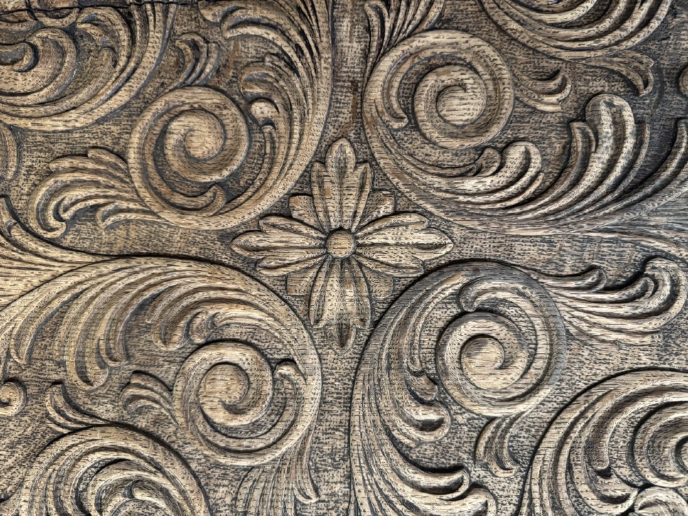 A hexagonal carved oak cricket table featuring elaborate foliate scrollwork on the tabletop and three turned legs joined by stretchers. View V