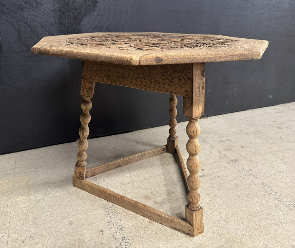 A hexagonal carved oak cricket table featuring elaborate foliate scrollwork on the tabletop and three turned legs joined by stretchers. View VII