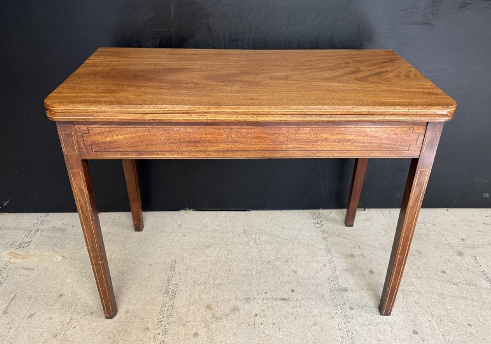 A rectangular Georgian mahogany fold-over tea table featuring fine boxwood string inlay and straight tapered legs.