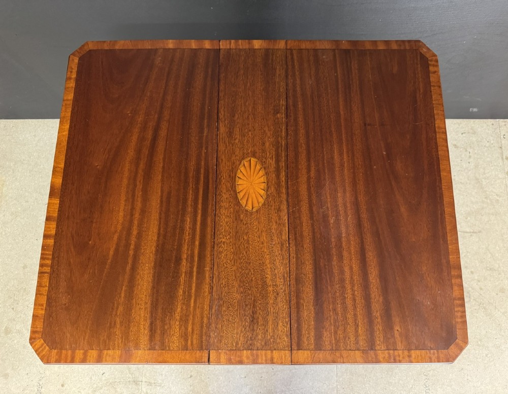 An Edwardian mahogany Sutherland table featuring drop leaves with satinwood crossbanding, central marquetry inlay, turned legs, and gateleg supports on castors. View VI