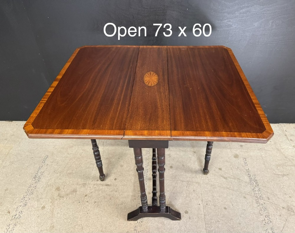 An Edwardian mahogany Sutherland table featuring drop leaves with satinwood crossbanding, central marquetry inlay, turned legs, and gateleg supports on castors. View X