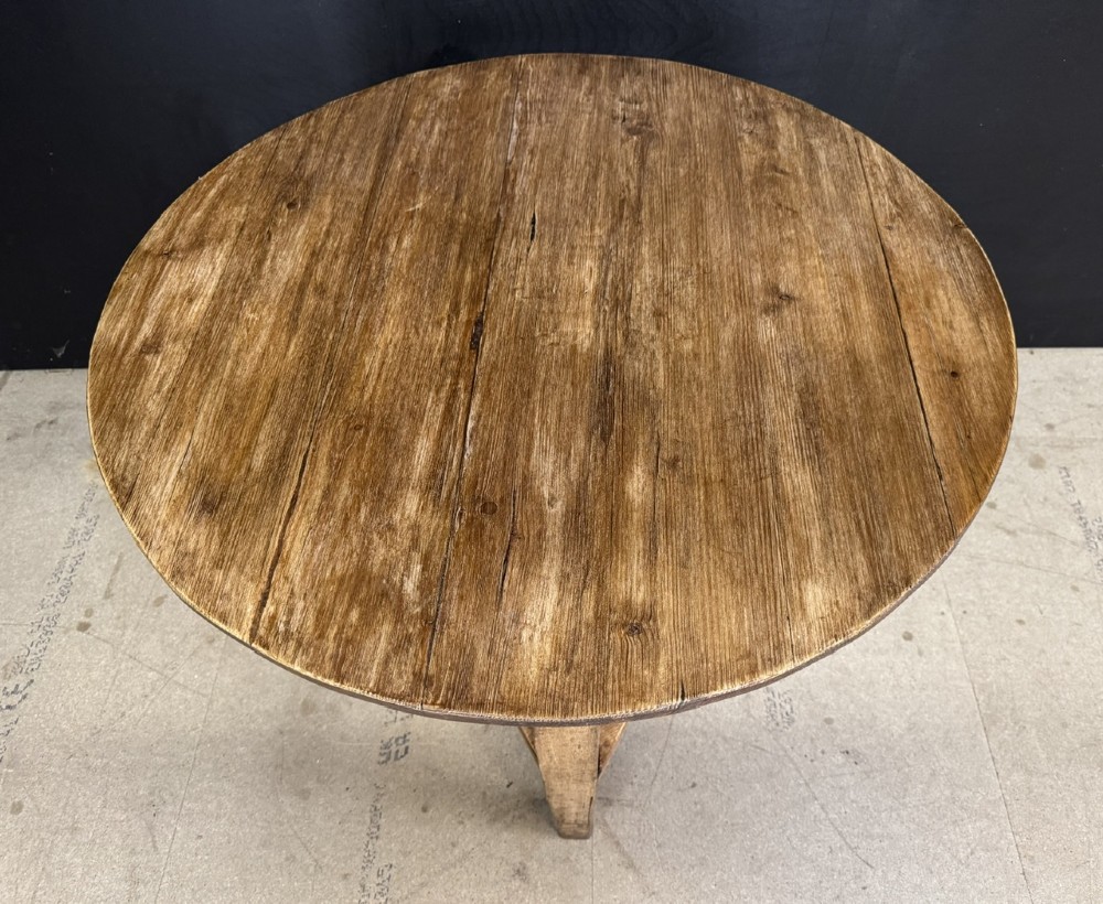 A rustic antique pine cricket table featuring a circular wooden top supported by three sturdy legs and a low triangular shelf. View III