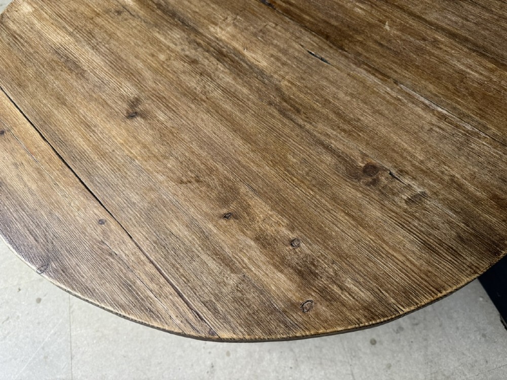 A rustic antique pine cricket table featuring a circular wooden top supported by three sturdy legs and a low triangular shelf. View VII