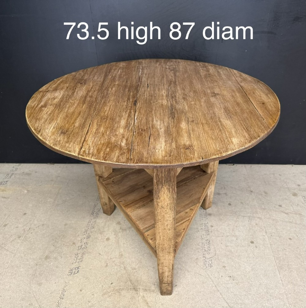 A rustic antique pine cricket table featuring a circular wooden top supported by three sturdy legs and a low triangular shelf. View VIII