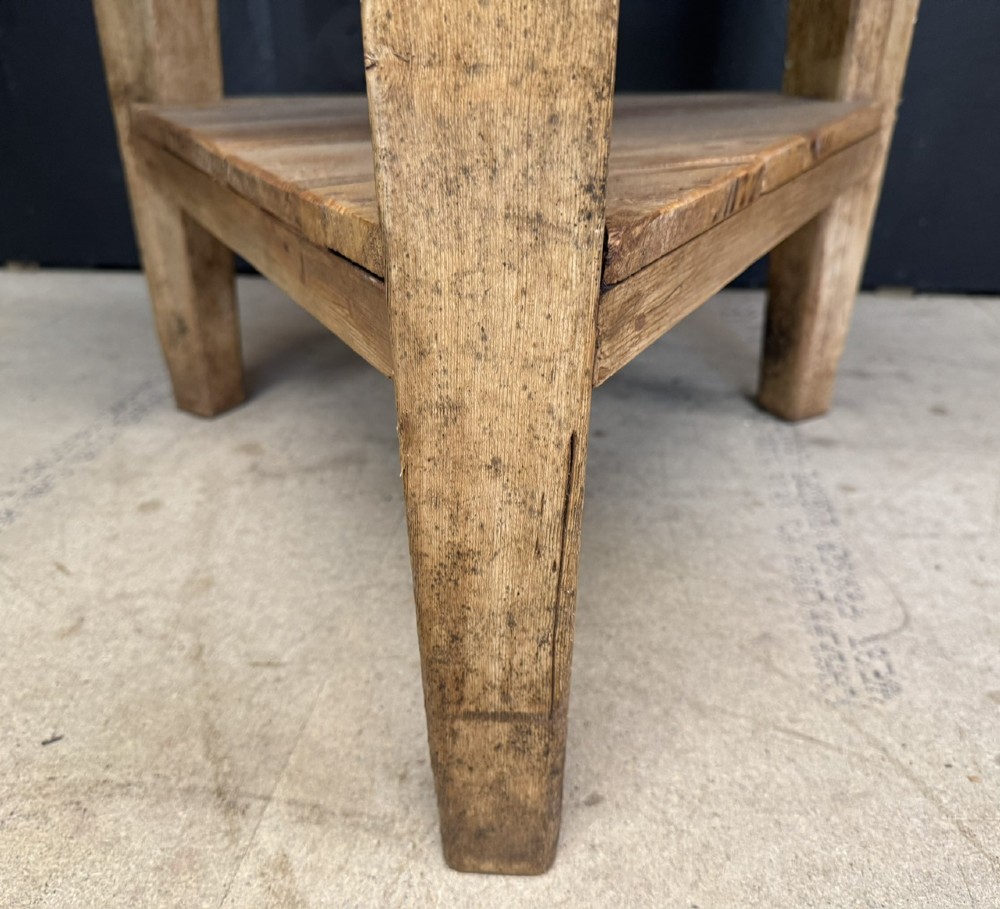 A rustic antique pine cricket table featuring a circular wooden top supported by three sturdy legs and a low triangular shelf. View X