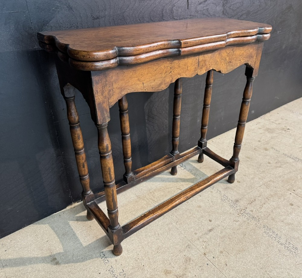 An antique walnut fold-over tea table with a shaped double top, contoured frieze, turned legs, and a lower box stretcher. View III
