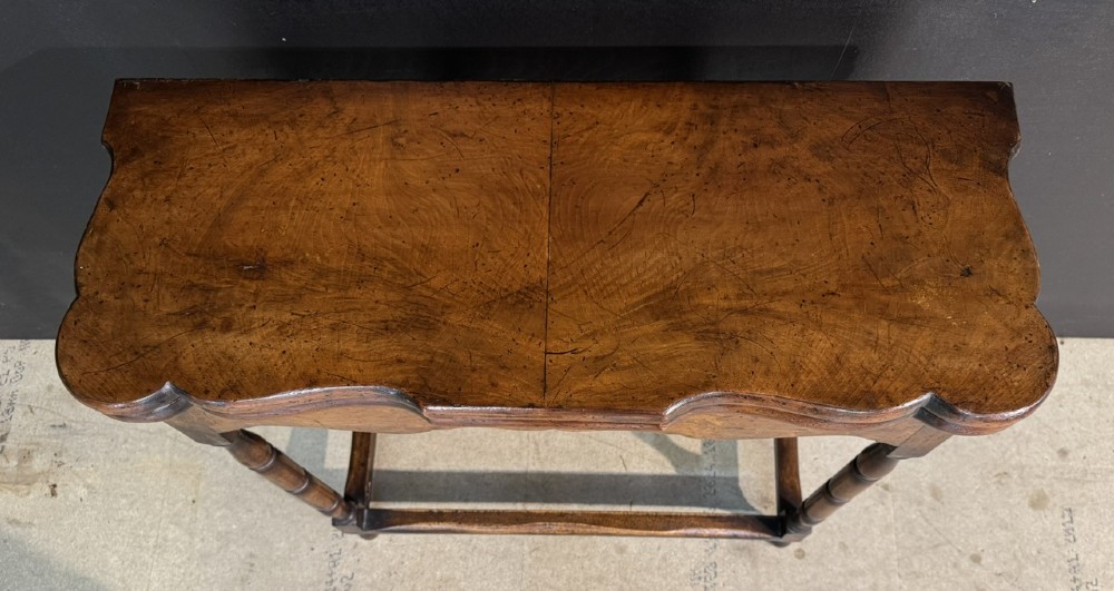 An antique walnut fold-over tea table with a shaped double top, contoured frieze, turned legs, and a lower box stretcher. View IV