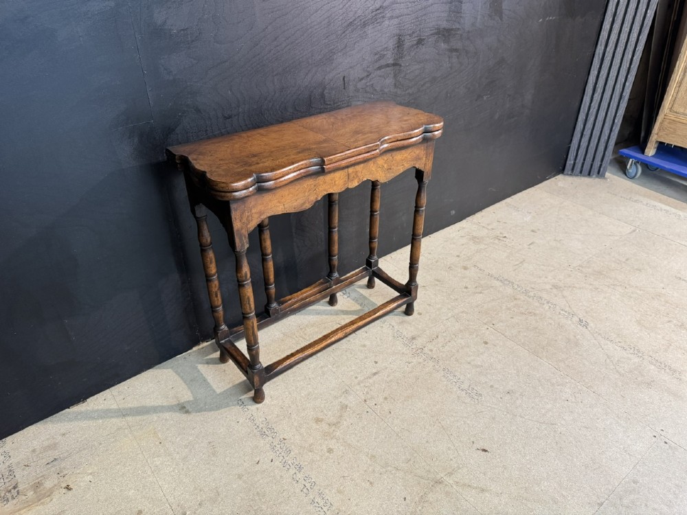 An antique walnut fold-over tea table with a shaped double top, contoured frieze, turned legs, and a lower box stretcher. View V