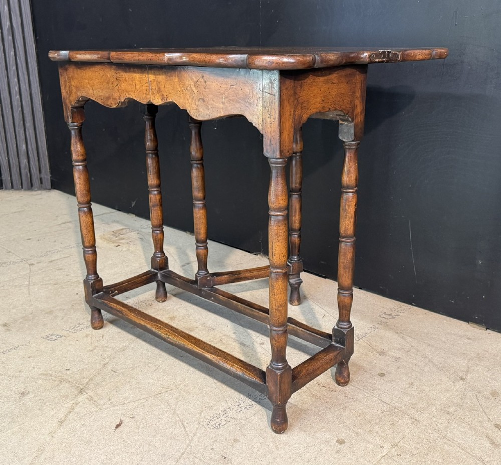 An antique walnut fold-over tea table with a shaped double top, contoured frieze, turned legs, and a lower box stretcher. View VIII