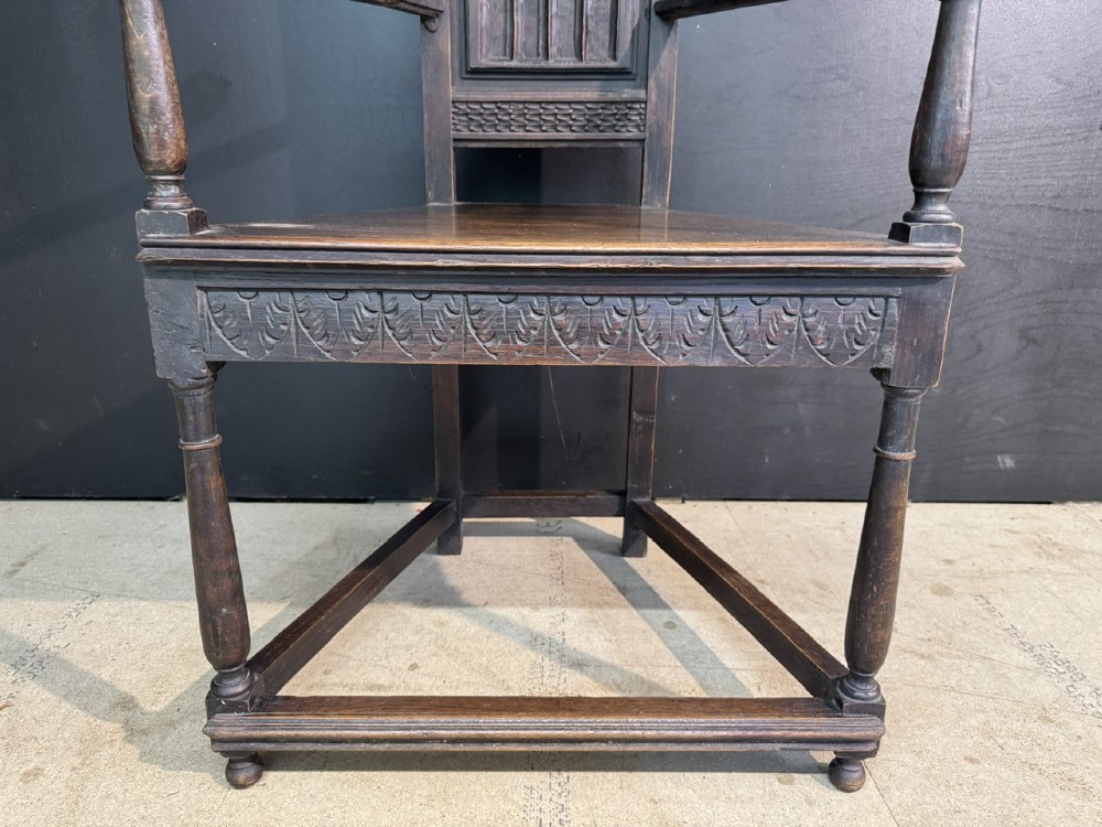 An antique dark oak open armchair featuring a tall carved back panel decorated with Gothic tracery motifs, curved armrests, and turned front legs. View III