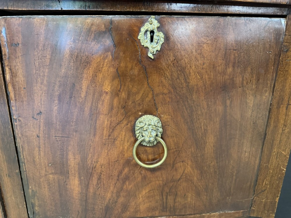 An antique Georgian mahogany bow-front sideboard featuring a central drawer, flanking cupboard doors, brass lion mask ring handles, and square tapered legs. View VI