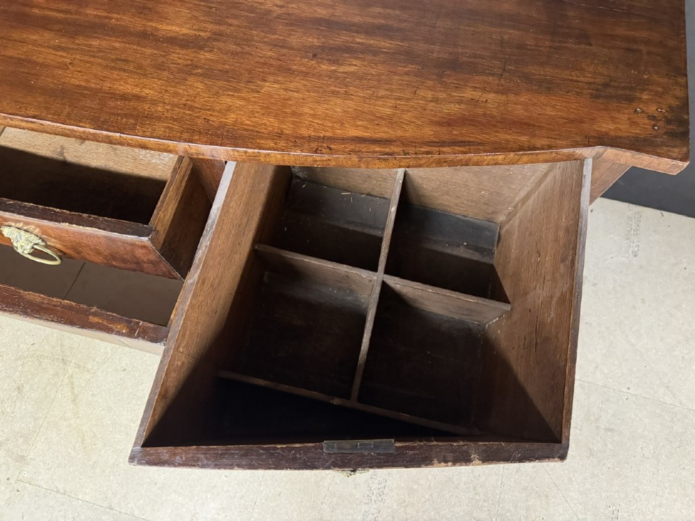 An antique Georgian mahogany bow-front sideboard featuring a central drawer, flanking cupboard doors, brass lion mask ring handles, and square tapered legs. View XI