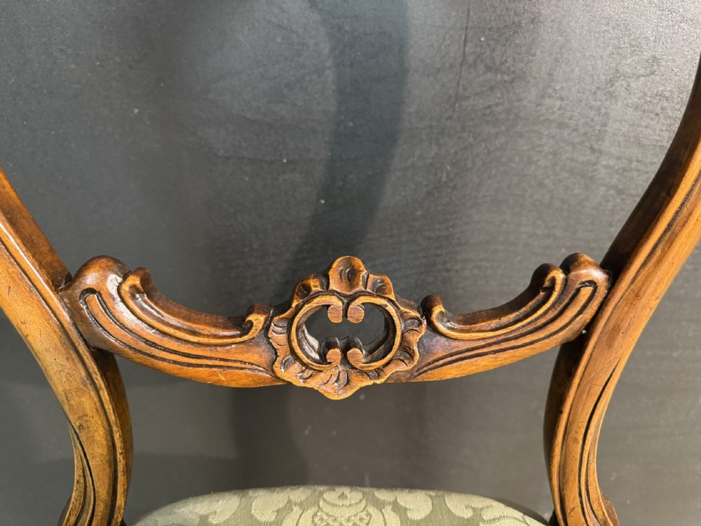 A Victorian balloon back side chair featuring a carved warm brown wood frame, cabriole front legs, and a sage green damask upholstered seat. View III