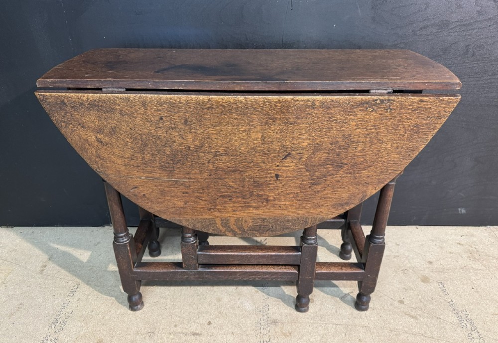 An eighteenth-century dark oak gateleg table featuring an oval drop-leaf top supported by turned legs and stretchers. View II